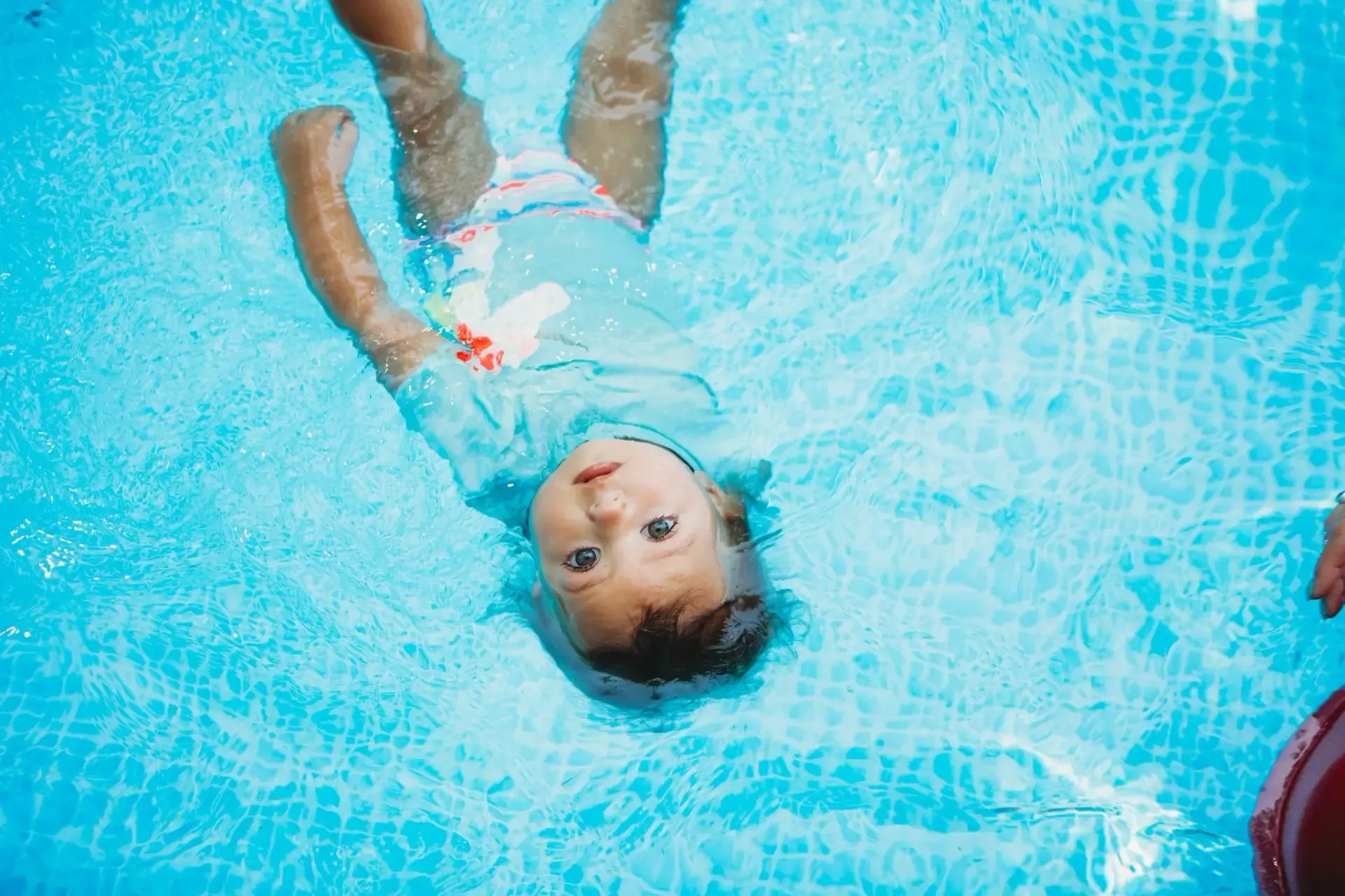 A young child floating calmly on her back in a swimming pool